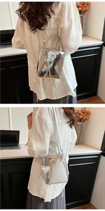 Silver metallic mini tote bag with heart charm and crossbody strap on female model
