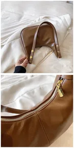 Détail macro de la fermeture éclair dorée et de la texture du sac à main en cuir marron