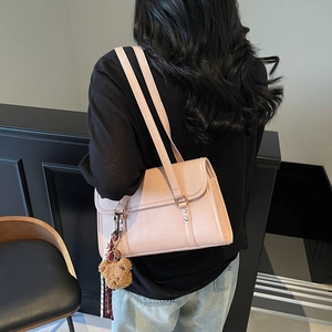 Chic pink crossbody bag with plush bear charm and scarf detail worn by a model