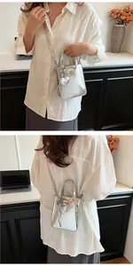 Detailed view of silver metallic mini tote with heart pendant and GOM GOM design