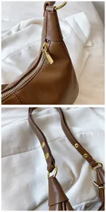 Détails d'un sac en cuir ciré marron avec quincaillerie dorée et fermeture à glissière