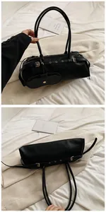 Detail view of black baguette bag featuring silver metal eyelets and a small detachable coin purse