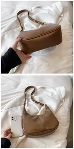 Détail du sac à bandoulière marron en demi-lune avec boucles dorées et téléphone