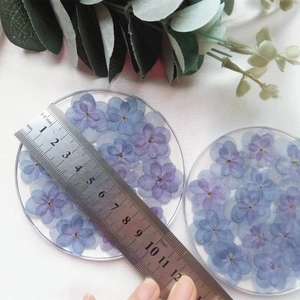 Detail shot of two resin coasters with real blue and purple dried hydrangea flowers