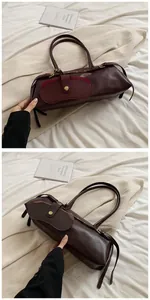 Detailed view of dark brown baguette bag with gold twist-lock front pocket and side straps