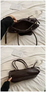 Detail of dark brown leather baguette bag with metal studs and striped fabric lining