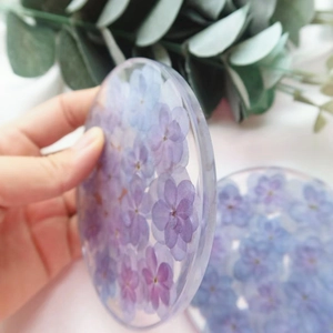 Handmade clear resin coaster with real purple and blue dried flowers in a round shape