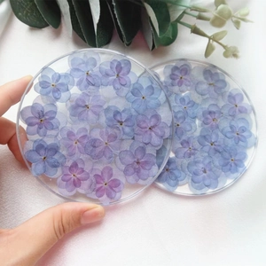 Detail showing transparent resin coaster with embedded purple dried flowers and clear finish