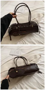 Detail of dark brown baguette bag with leather buckles, metal rings and mini pouch