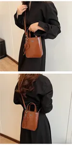 Detail showing brown oil wax leather crossbody bag with heart charm and top handle