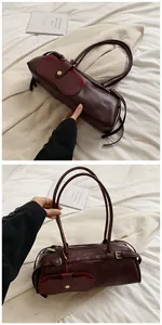 Detail of burgundy leather baguette bag showing vintage hardware and magnetic flap pocket