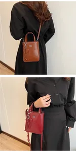 Detail view of vintage oil leather crossbody square bag with heart charm and shoulder strap