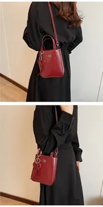 Detail of red faux leather crossbody bag with top handles and heart pendant