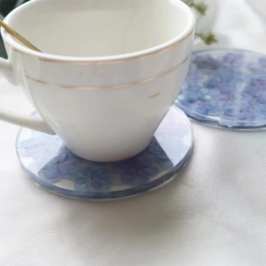 Detailed macro view of resin coasters with blue and purple flowers on white silk