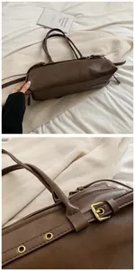 Detail of adjustable strap and vintage gold buckle on a brown leather baguette shoulder bag