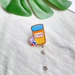 Detail of acrylic retractable nurse badge holder with glitter vitamin bottle design