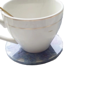Handmade clear resin coaster with purple dried flowers and gold rim teacup on top