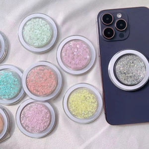 Close-up of colorful glitter MagSafe phone sockets in mint, pink and silver on silk