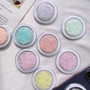 Macro shot of assorted colorful glitter flakes in clear round plastic storage jars