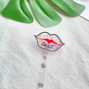Detail of red lips acrylic badge reel with colorful sequins and Smile text on fabric