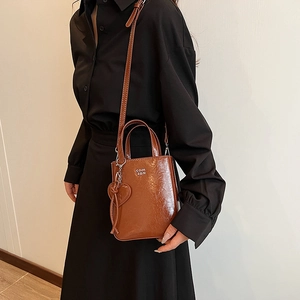 Brown glossy leather mini tote bag with silver lettering and heart charm on long strap