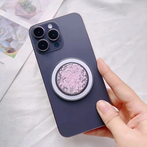 Pink glitter MagSafe phone grip with silver frame attached to a purple smartphone