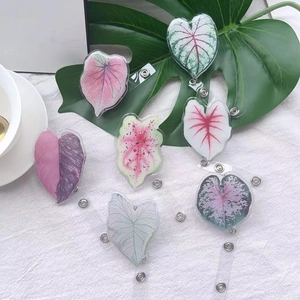 Detail of 7 colorful leaf shaped acrylic retractable badge reels on a white fabric surface