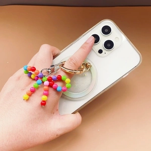 Colorful beaded bow phone charm with a golden round spring clasp on a mobile device