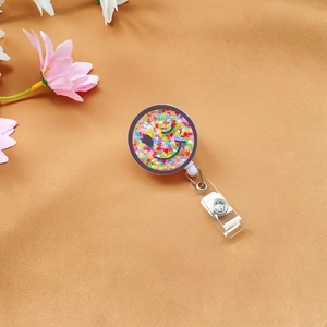 Detail of acrylic star glitter badge reel with a winking smiley face design