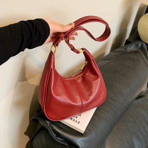 Sac hobo chic en cuir ciré rouge avec anneaux dorés présenté dans un décor de style