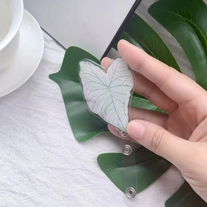 Detail of heart leaf acrylic badge reel with translucent texture held in hand