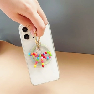 Close-up of colorful beaded bow phone charm attached to a gold ring on a white phone case