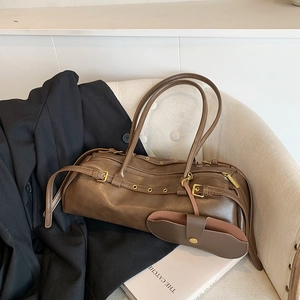 Vintage brown baguette bag with gold hardware and glasses case on a beige chair