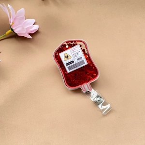 Macro view of medical-themed acrylic badge reel with blood bag glitter and logo