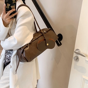 Retro dark brown cylindrical baguette bag with metal eyelets and small leather charm accessory
