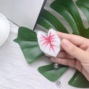 Close-up of retractable acrylic badge holder featuring a red leaf pattern on white fabric