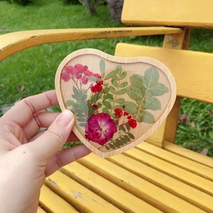 Macro shot of heart-shaped wooden resin coaster with real pressed flowers and leaves