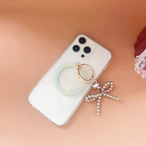 Close-up of pearl bow charm and magnetic ring holder on clear phone case surface