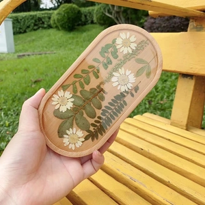 Detailed view of an oval wood resin coaster with embedded real white daisy flowers