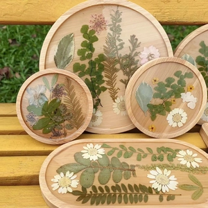 Close-up of wooden resin trays with real dried flowers on a rustic garden bench
