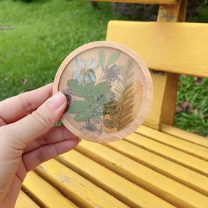 Detailed view of a handmade round resin coaster with real pressed flowers and wood frame