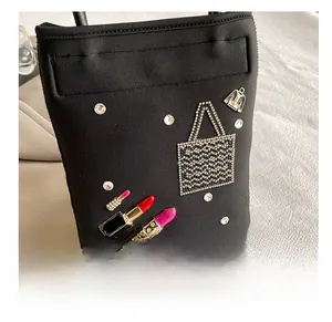 Detail of black fabric envelope bag with rhinestone accents and lipstick charms