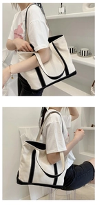 Detail view of large canvas tote bag with black contrast piping and sturdy shoulder handles