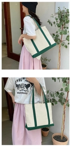 Close-up of a large capacity canvas tote bag in off-white with dark green handles