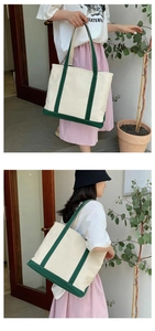Detail of a large canvas tote bag in beige and green, showing hand-carry and shoulder wear