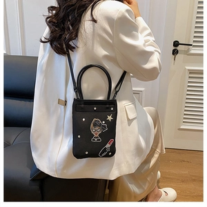 Detail view of black envelope crossbody bag with sparkle patches on model back