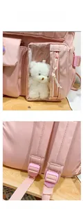 Detailed view of pink school backpack featuring a plush bear in a transparent pocket