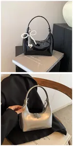 Détail de sacs hobo en cuir verni noir et argent métallisé avec breloques noeud de perles
