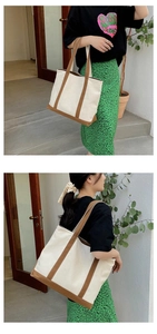 Detailed view of cream canvas tote bag with brown straps shown on a shoulder