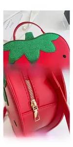 Close-up of strawberry shaped bag with green sequin leaves and gold zipper details